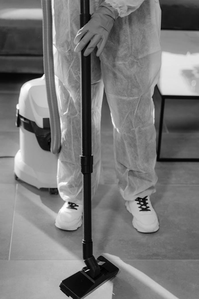 Monochrome image of a person in PPE vacuuming indoors. Suitable for COVID-19 and hygiene concepts.